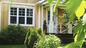 A house with a front porch, a window, and a small garden. - Charlevoix -  Chalet Le Cormier (Saint-Aimé-des-Lacs)