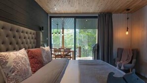 A bedroom with a large bed, a wooden headboard, a small table, and a chair.