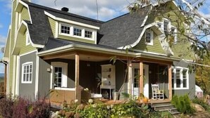 Una casa de dos pisos con un porche, una puerta principal y un pequeño jardín.