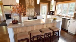 Una cocina moderna con una isla central, taburetes de bar, lavavajillas y estufa.