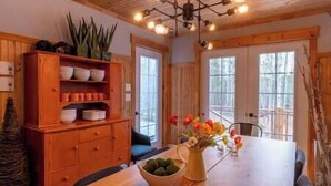Ein Holztisch mit einer Blumenvase, einer Obstschale und einem Schrank mit Geschirr.