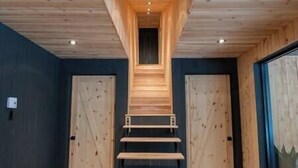 Un escalier en bois menant à un plafond sombre, flanqué de deux portes.