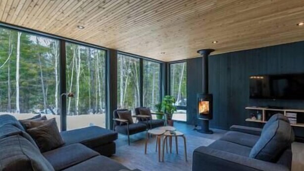 Un salon moderne doté d’une grande fenêtre, d’une cheminée et d’un téléviseur.