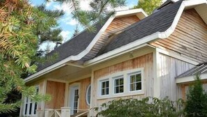 Ein zweistöckiges Holzhaus mit Veranda und überdachter Eingangshalle.
