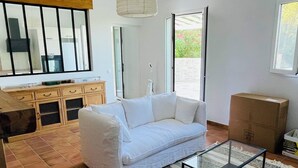 Ein modernes Wohnzimmer mit einem weißen Sofa, einem Glastisch und einem gemusterten Teppich.