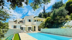 Ein Poolbereich mit einem klaren, blauen Pool, einer Rasenfläche und einem Gebäude mit vielen Fenstern und einem Balkon.