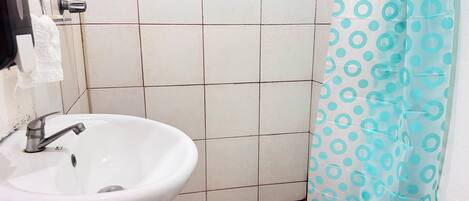 A bathroom with a white sink, a shower curtain with blue circles, and tiled walls.