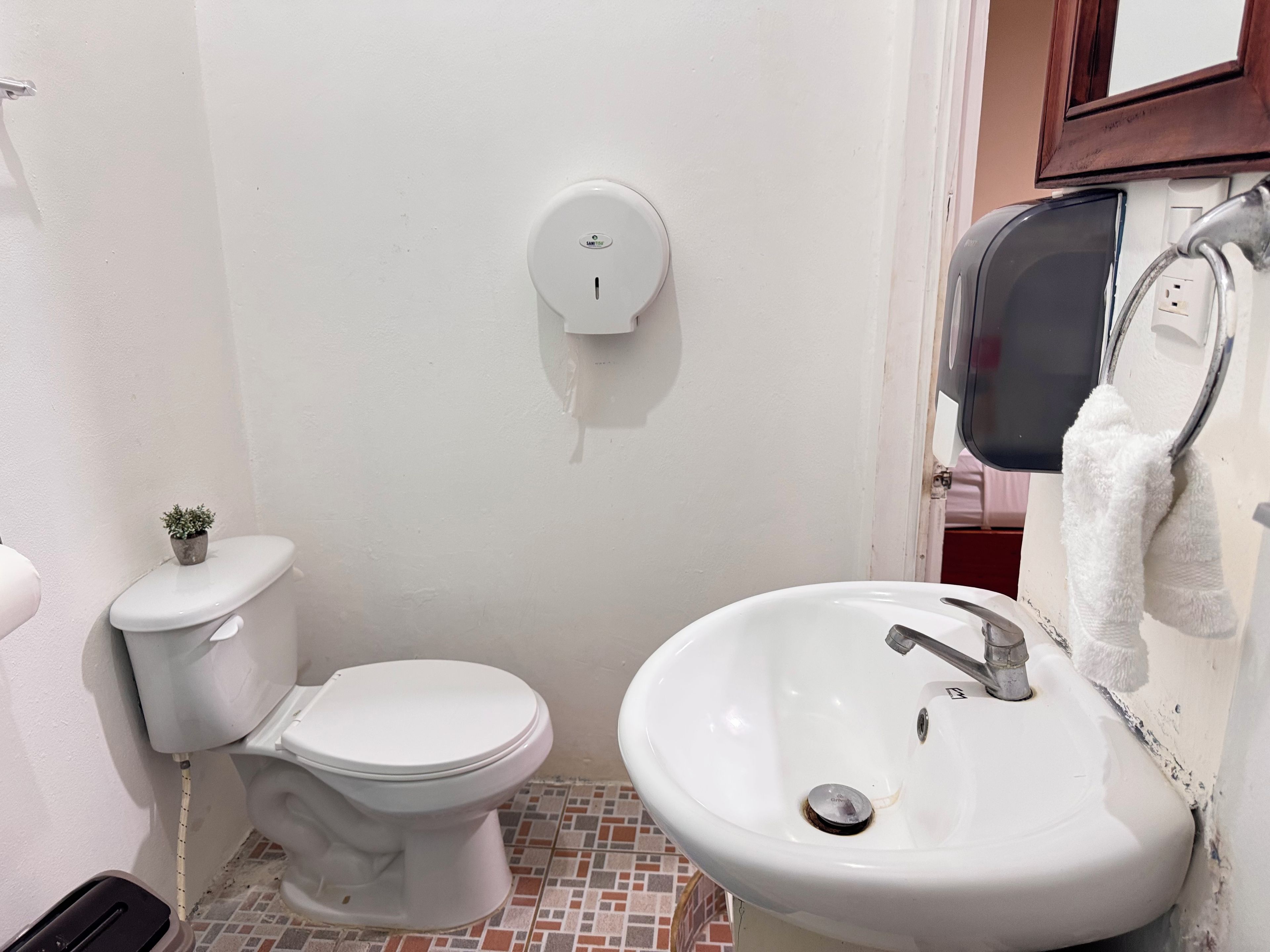 A bathroom with a toilet, sink, and a hand dryer mounted on the wall.