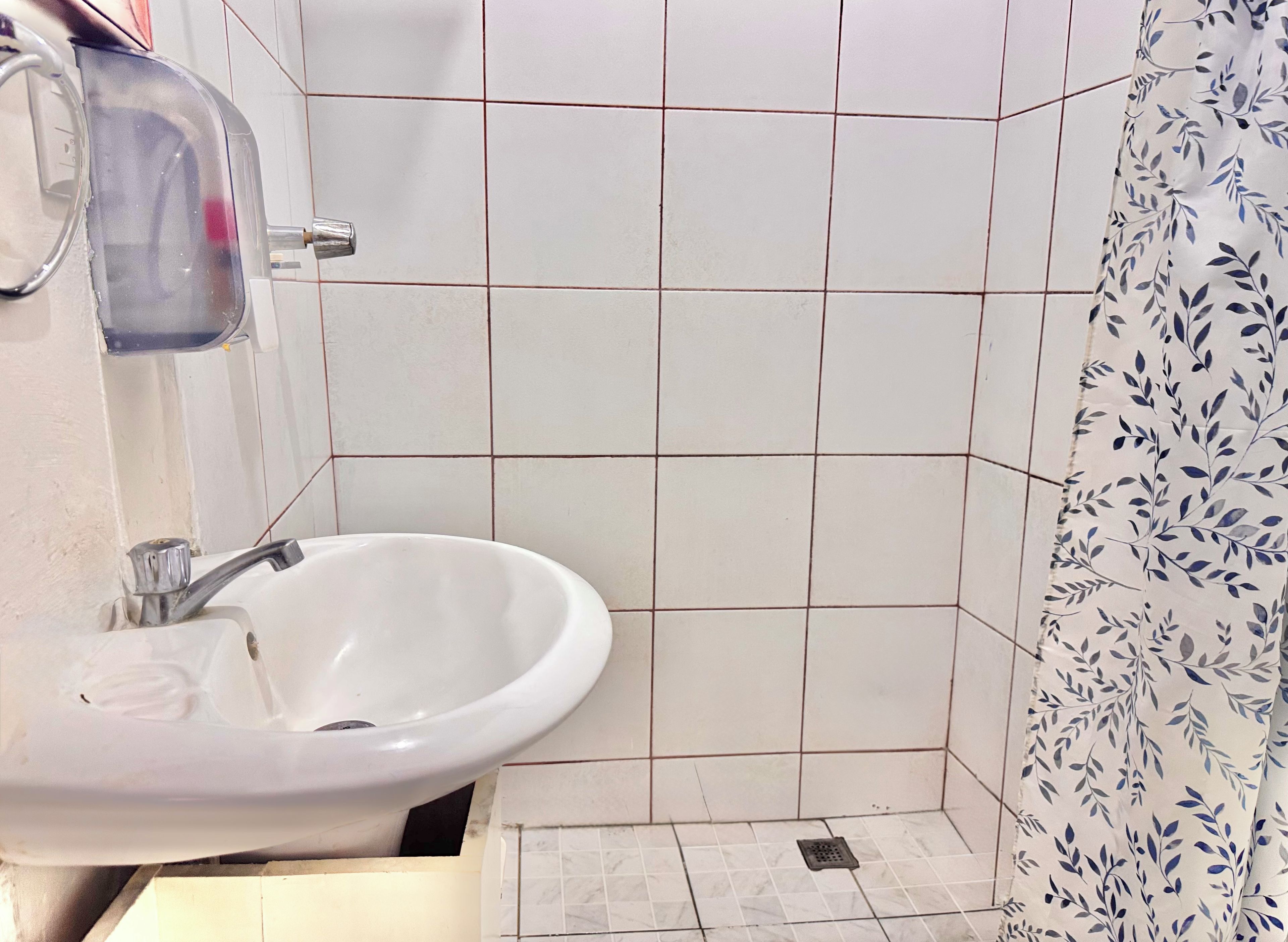 Une salle de bain avec un lavabo blanc, un miroir et des murs carrelés.