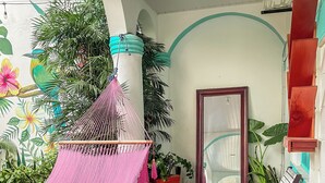 Un rincón interior acogedor con una hamaca, sillas de madera y piso a cuadros.
