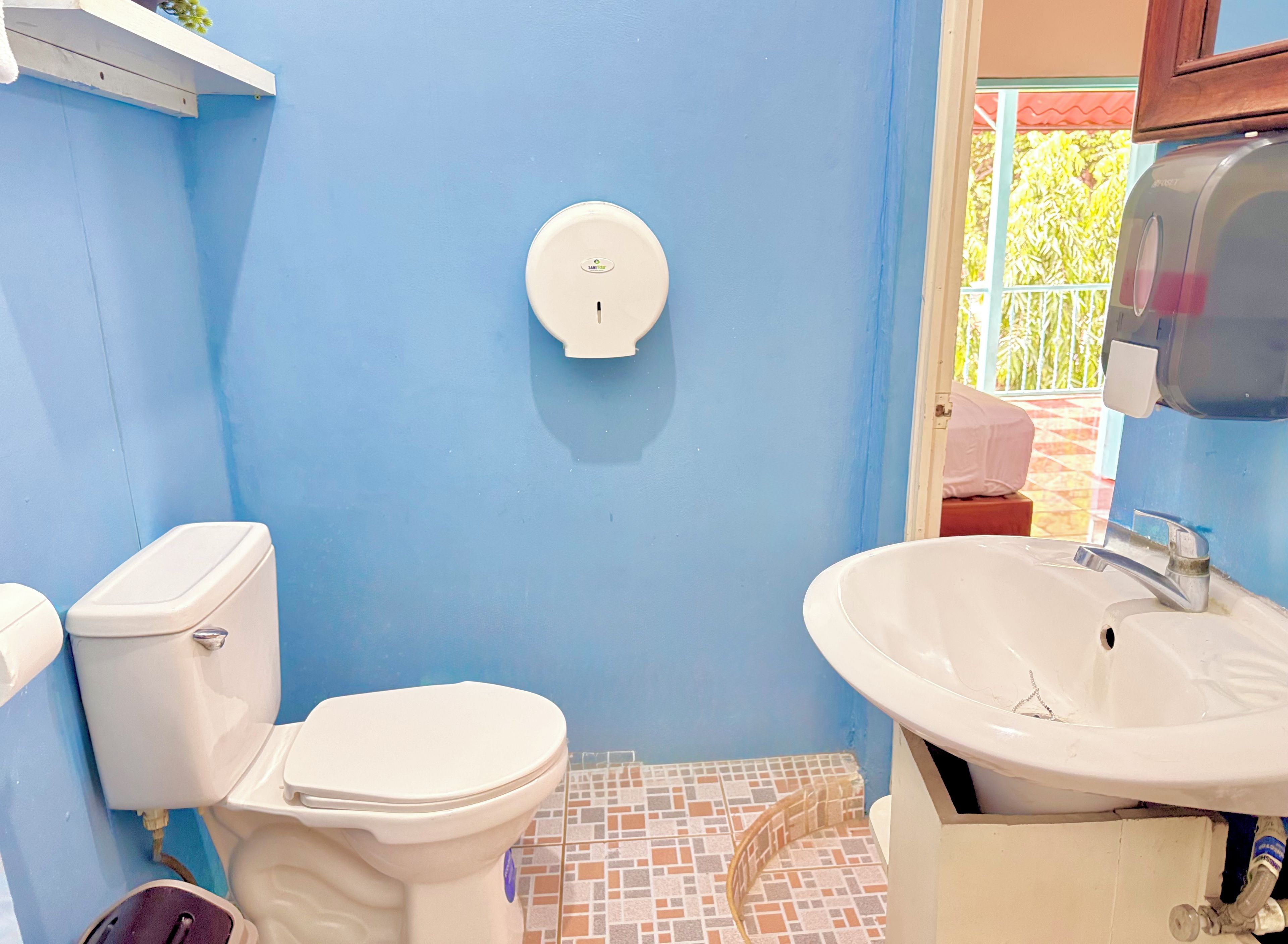 Casa de banho com sanita, lavatório e dispensador de sabonete fixado na parede.