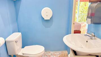 Casa de banho com sanita, lavatório e dispensador de sabonete fixado na parede.