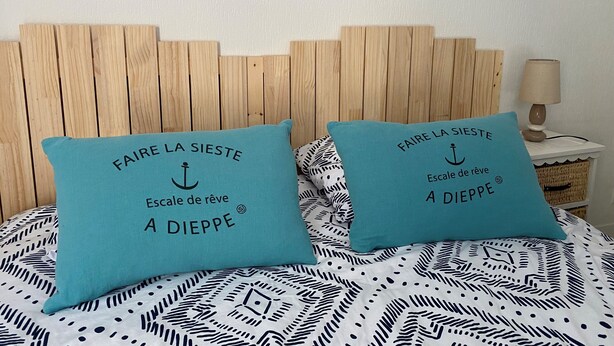 A bed with two turquoise pillows, each with text in French.
