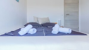Un lit bien fait, avec des serviettes pliées, un oreiller et une table de chevet sur laquelle se trouve une lampe.