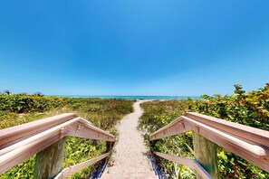 A wooden boardwalk leading to a beach with clear skies.