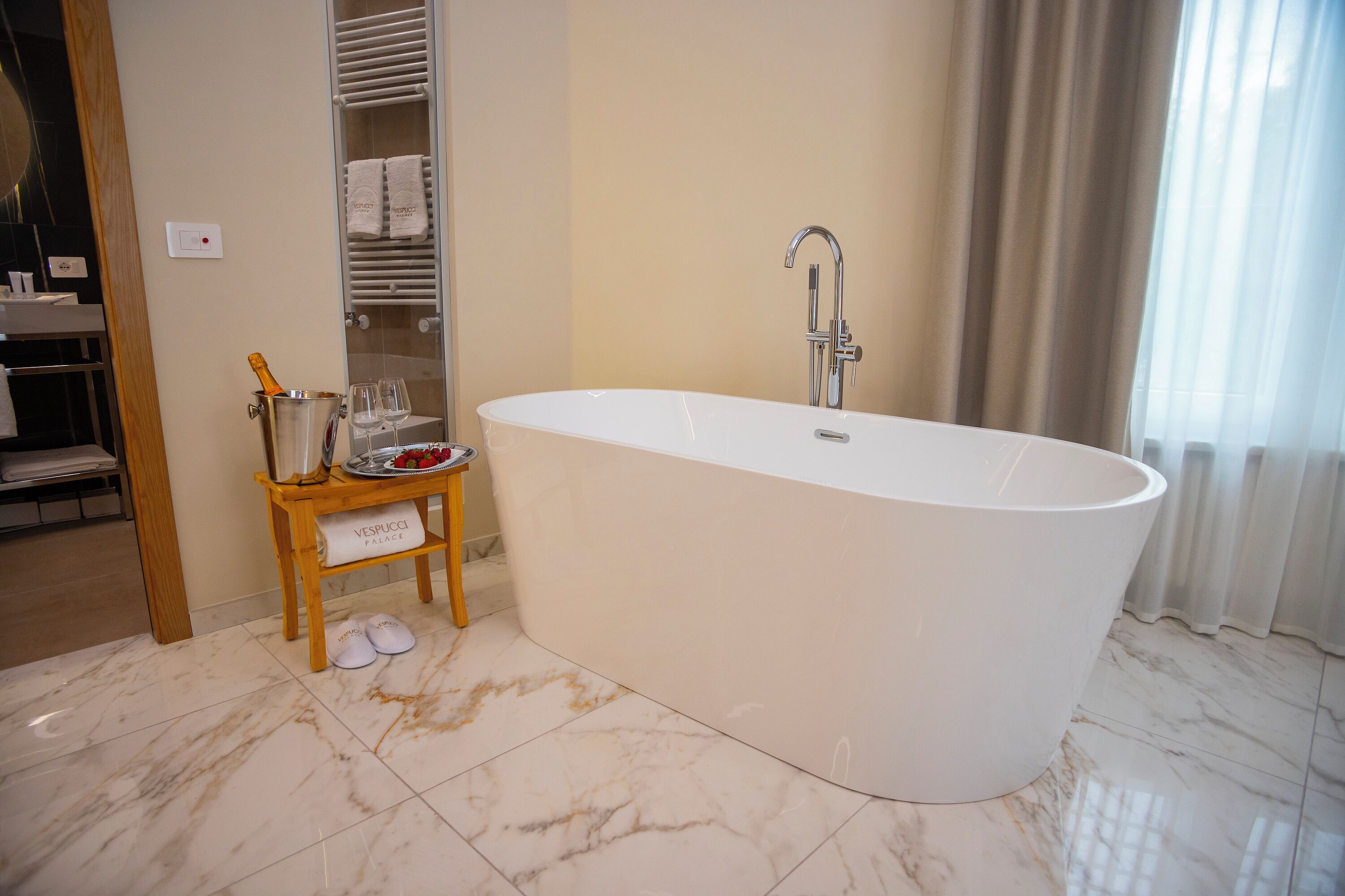 A modern bathroom with a freestanding bathtub, a wooden vanity with toiletries, and a towel rack.