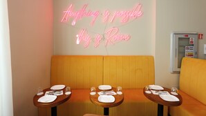 A restaurant interior with neon signage, wooden tables, and yellow cushioned seating. - Vespucci Palace (Rome)