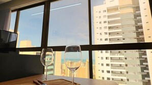 A modern interior with a large window, a wine glass, and a decorative ceiling light. - Co-House (João Pessoa)