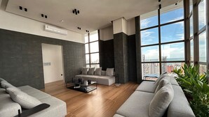 A modern living room with a sofa, a coffee table, and a view of the city. - Co-House (João Pessoa)