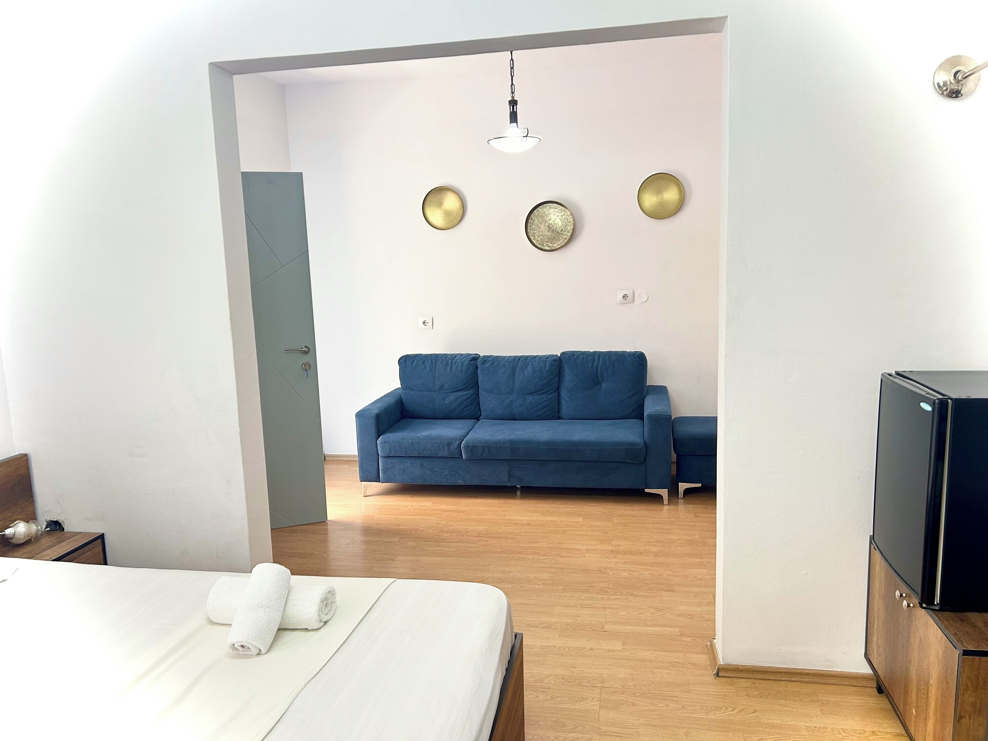 A modern hotel room with a bed, a blue sofa, and a TV.