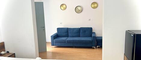 A modern hotel room with a bed, a blue sofa, and a TV.