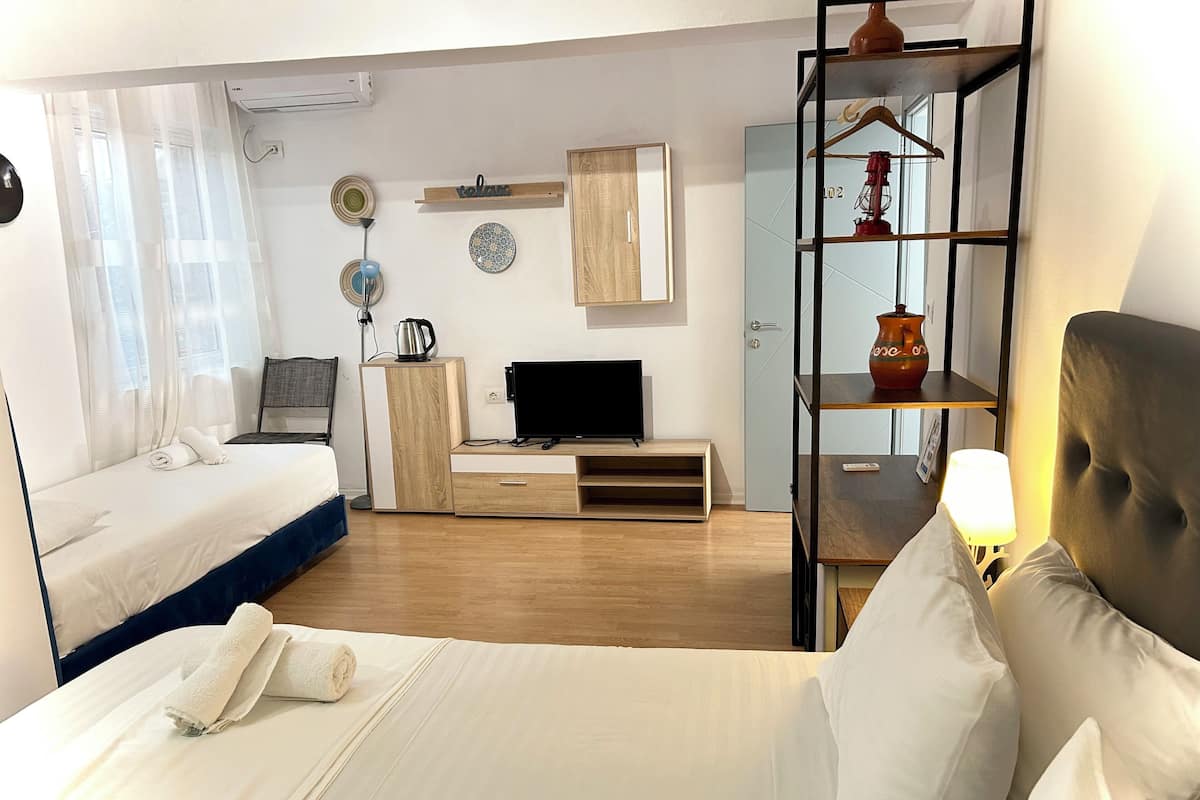 Habitación de hotel con dos camas, televisión, escritorio y armario.
