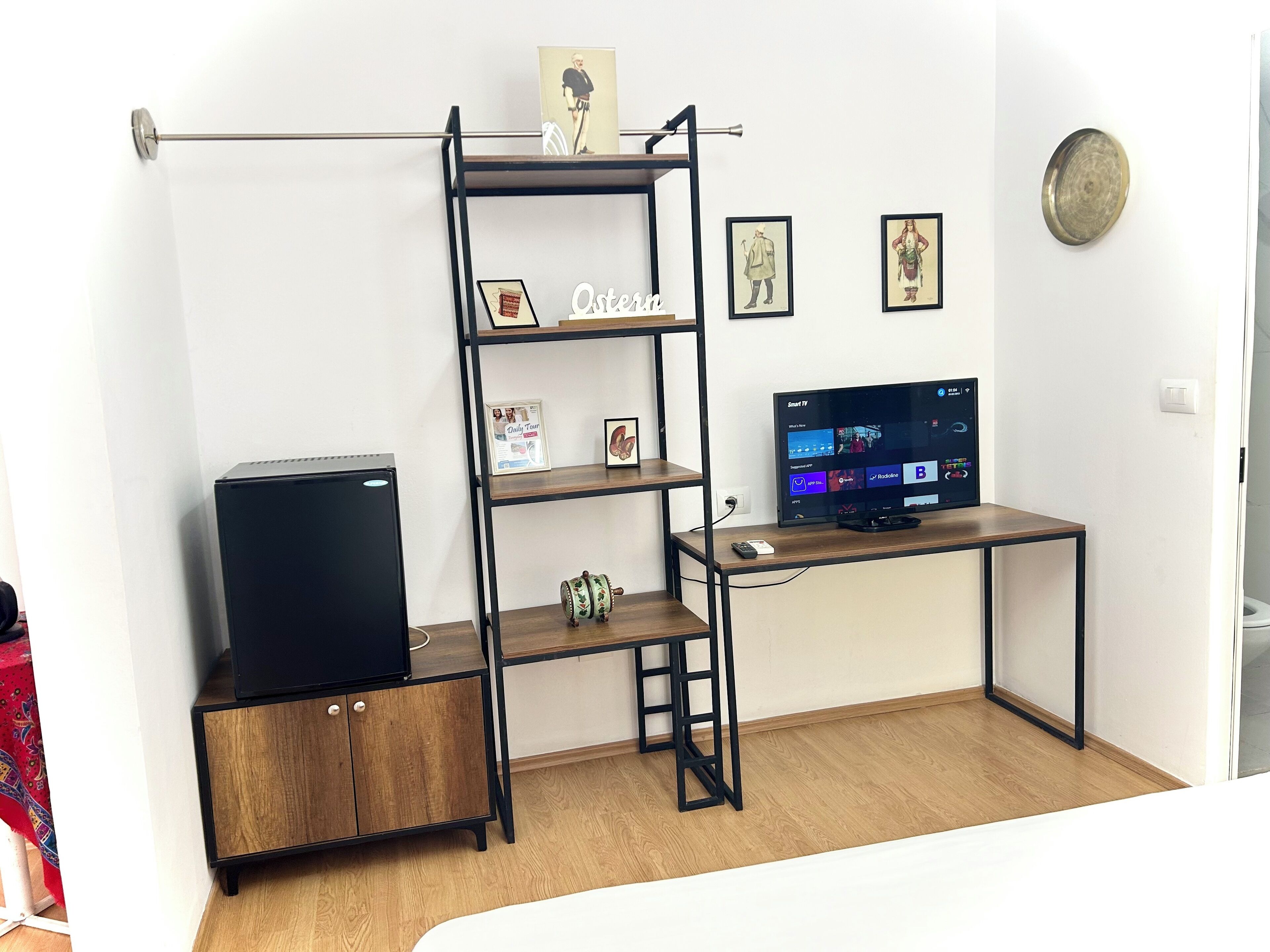 Una sala de estar moderna con un mueble de televisión de madera, una estantería metálica negra y un mueble bajo.