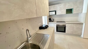 A modern kitchen with a stainless steel sink, a microwave, and a built-in oven. - Rosoglio Poreč 300m from sea, new apartment 2024 (Poreč)