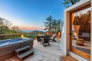 A deck with a hot tub, seating, and a view of the landscape.