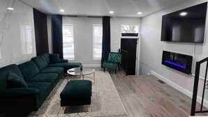 Una sala moderna con un sofá modular, una mesita redonda y un sillón verde.
