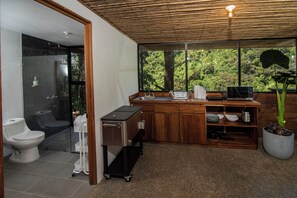 Une salle de bain moderne dotée d’une douche à parois de verre, de toilettes et d’un espace lavabo avec un plan de travail et des étagères en bois.