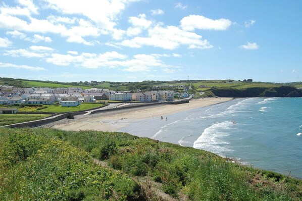 A coastal town with a sandy beach, a promenade, and buildings along the shore.