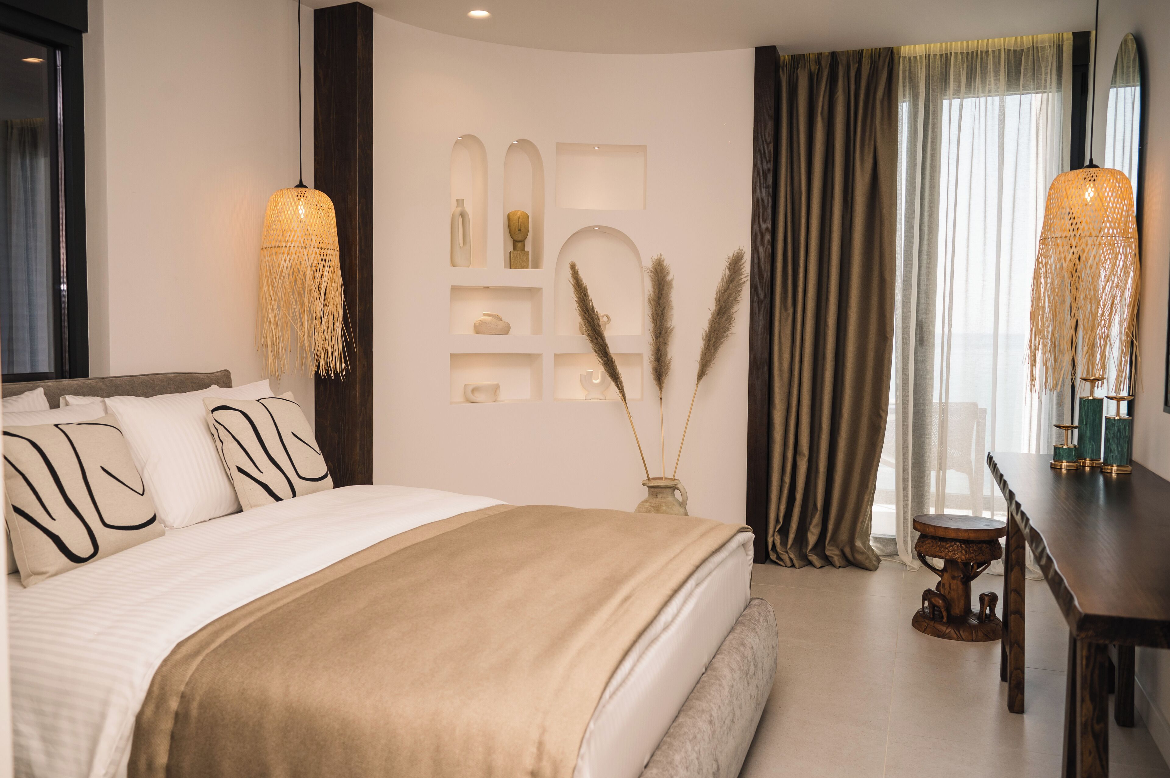 A modern hotel room with a large bed, a wooden side table, and a decorative wall unit.