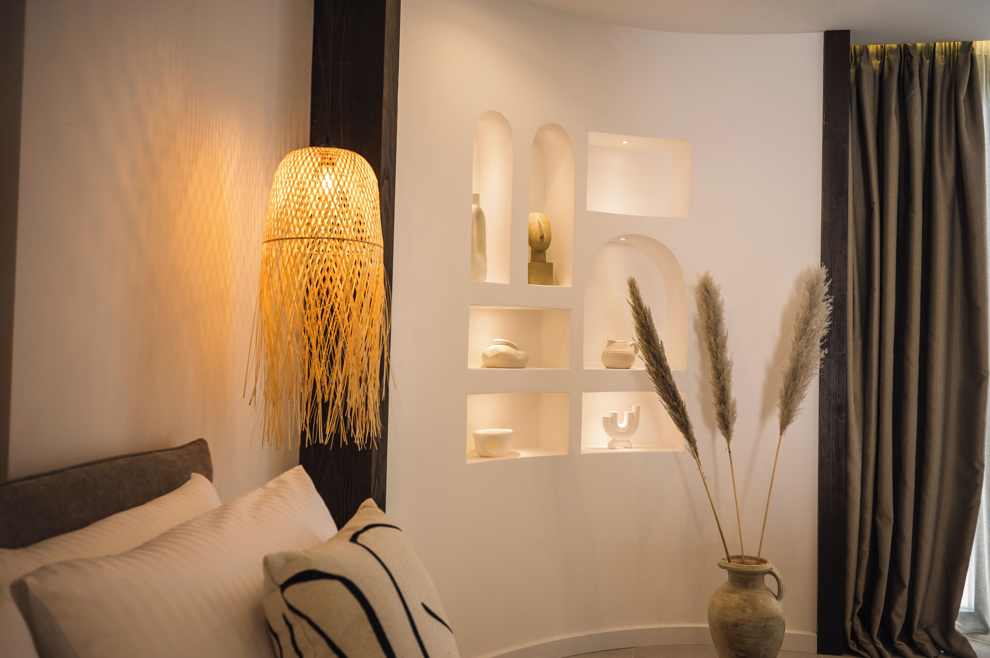 A modern bedroom with a bed, a wall-mounted lamp, and decorative shelves.