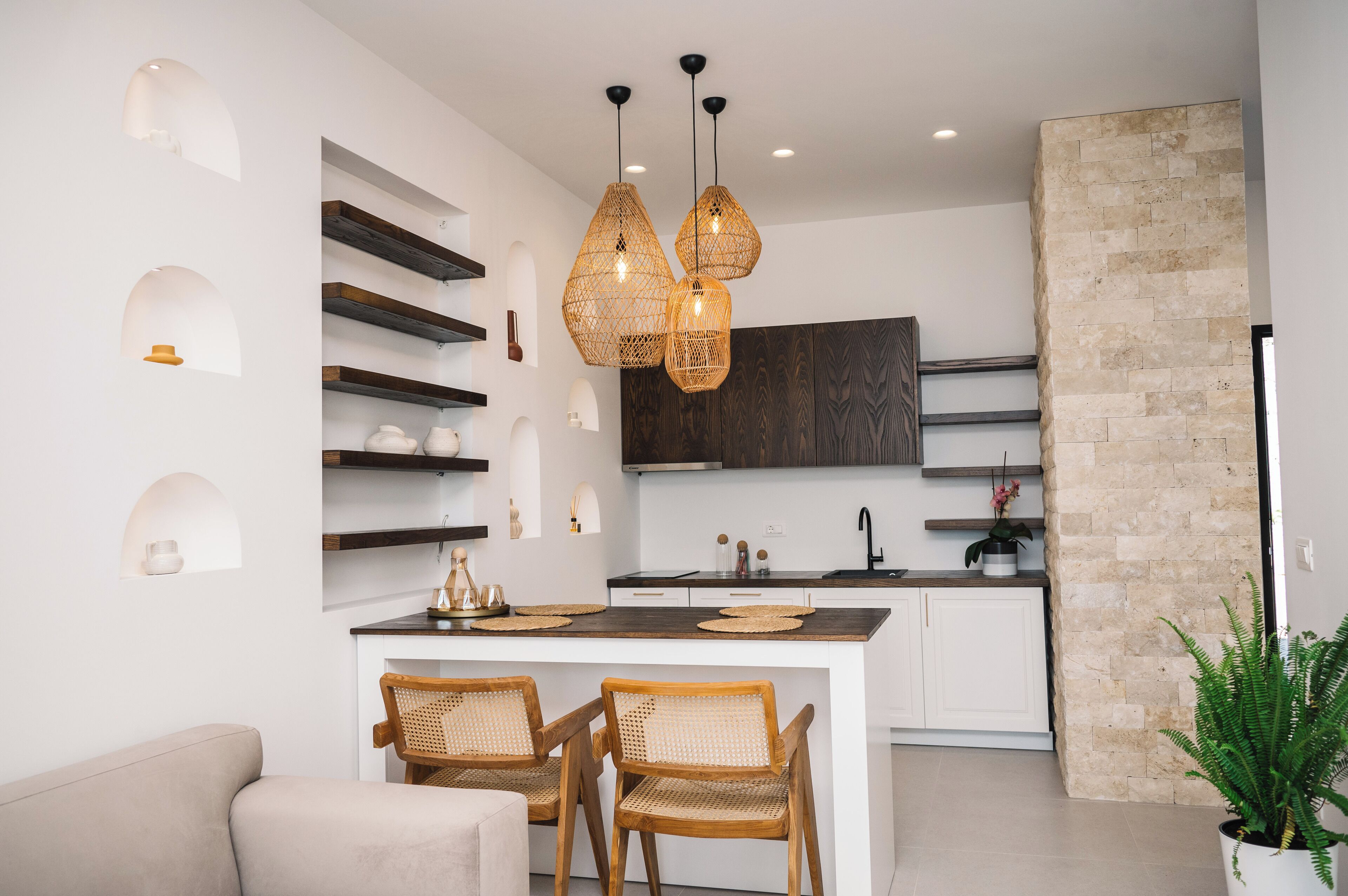 A modern kitchen with a central island, wooden chairs, and pendant lighting.