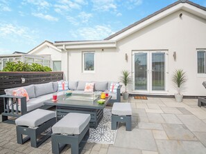 A patio area with a sofa set, a glass-top table, and potted plants.