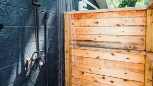 A wooden fence, a black wall, and a showerhead with water flowing. - The Cottage (Bellaire)