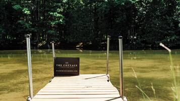 A wooden dock leading into a lake with a sign that reads "The Cottage."