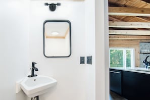 Une salle de bain moderne avec un lavabo blanc, un robinet noir et un miroir à cadre noir.