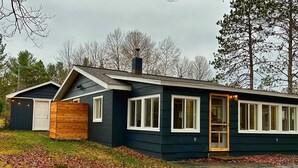A modern two-story house with a dark exterior, white trim, and large windows. - The Cottage (Bellaire)