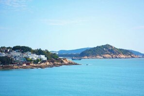 A coastal town with buildings along the shore, a prominent hill, and calm sea. - Dongshan Haizhiyuan Apartment (Dongshan County)