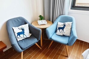 Two armchairs with decorative pillows, a small round table with a plant, and a window with curtains. - Dongshan Haizhiyuan Apartment (Dongshan County)