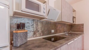 Een keuken met een ingebouwde magnetron, een spoelbak en een marmeren aanrecht.
