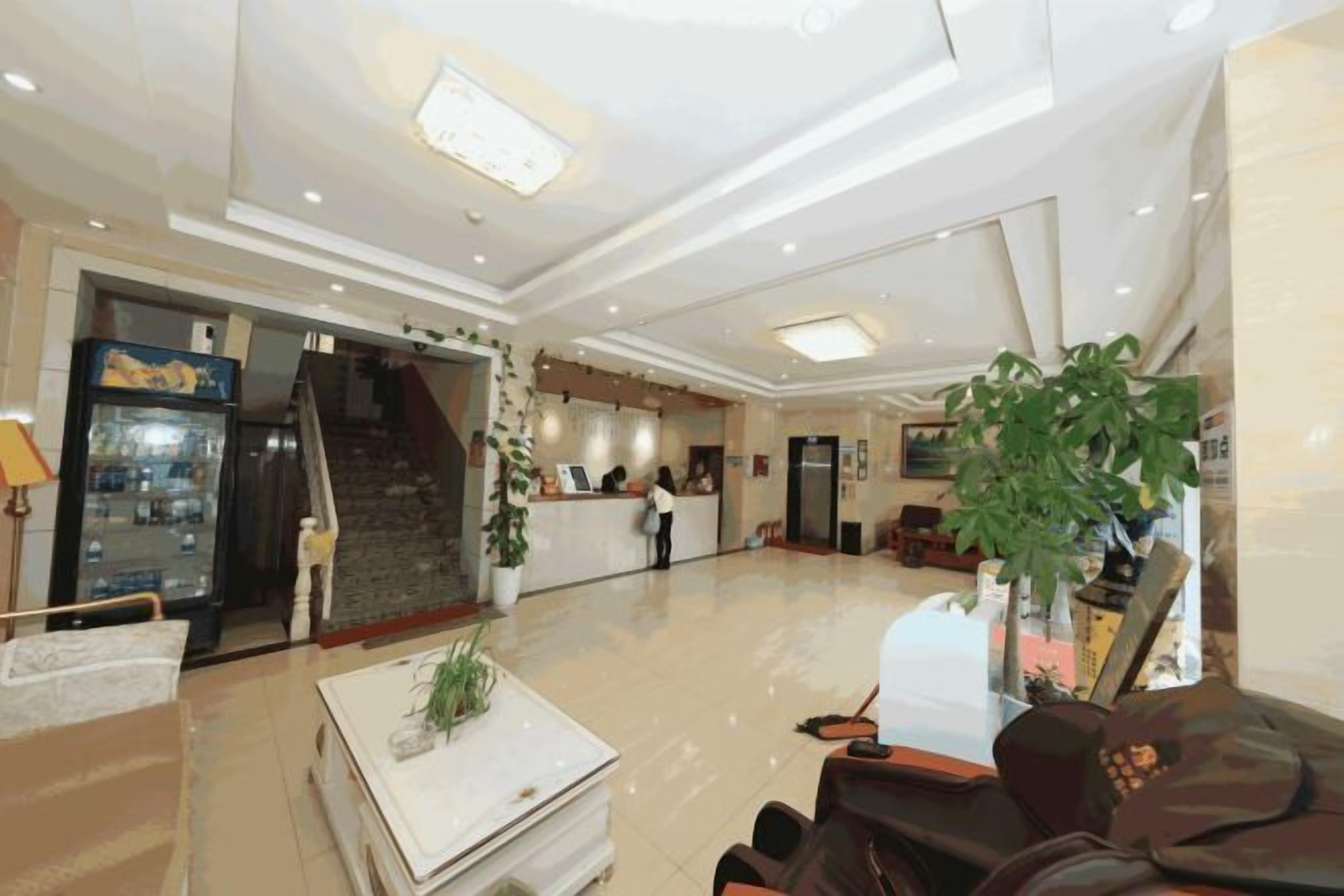 Un vestíbulo de hotel con una recepción, una escalera y una zona de estar.