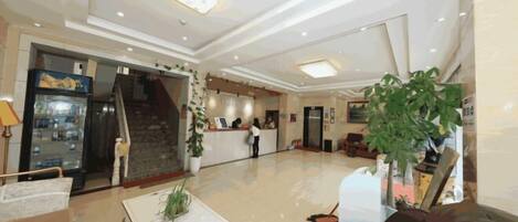 Un vestíbulo de hotel con una recepción, una escalera y una zona de estar.