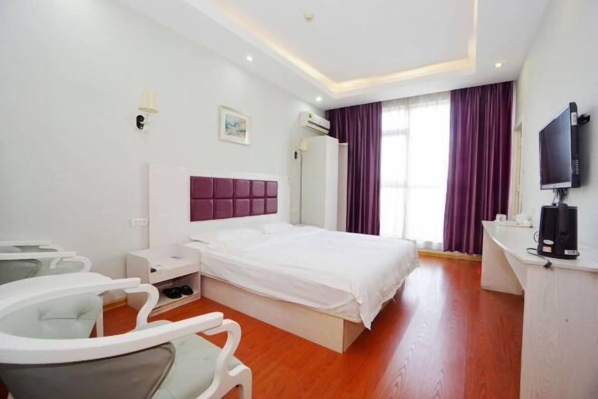 Ein Hotelzimmer mit Bett, Schreibtisch, Stuhl, Fernseher und Klimaanlage.