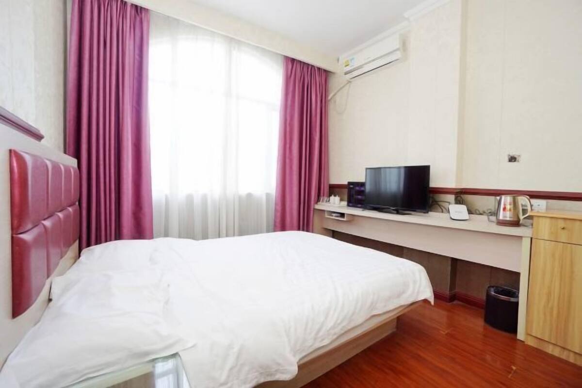 Ein Hotelzimmer mit einem Bett, einem Schreibtisch mit Fernseher und einem kleinen Schrank.