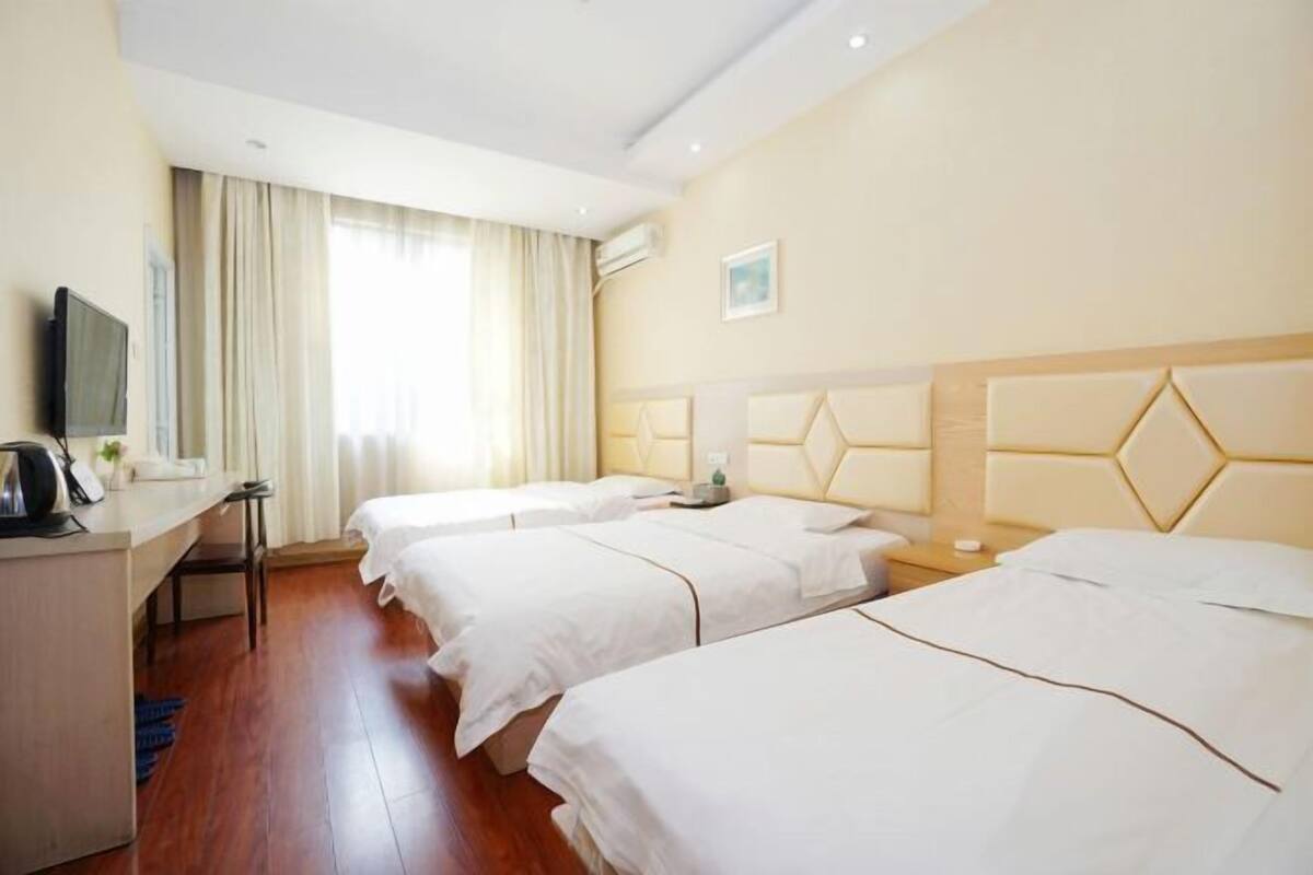 Ein Hotelzimmer mit zwei Betten, einem Schreibtisch, einem Stuhl und einem Fernseher.