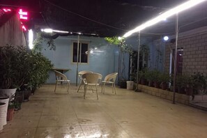 An outdoor patio area with potted plants, a table, and chairs.