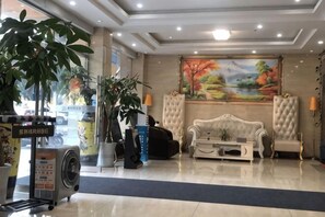 Eine Hotellobby mit einem großen Gemälde, einer Couch, einem Sessel und einer Zimmerpflanze.